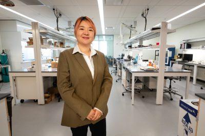 Materials science researcher stands in lab.